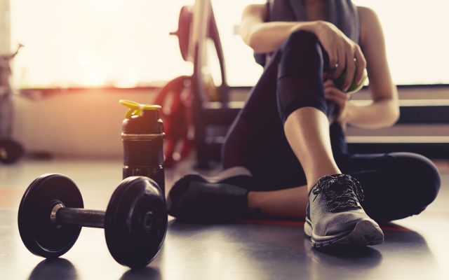 Woman exercise workout in gym fitness breaking relax holding apple fruit after training sport with dumbbell and protein shake bottle healthy lifestyle bodybuilding.