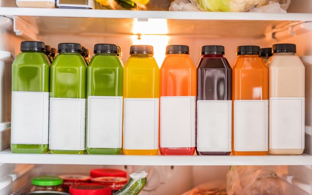 Juicing cold pressed vegetable juices for a detox cleanse diet. Dieting bydrinking organic fruits and vegetables juice made fresh and delivered in bottles at home in fridge.